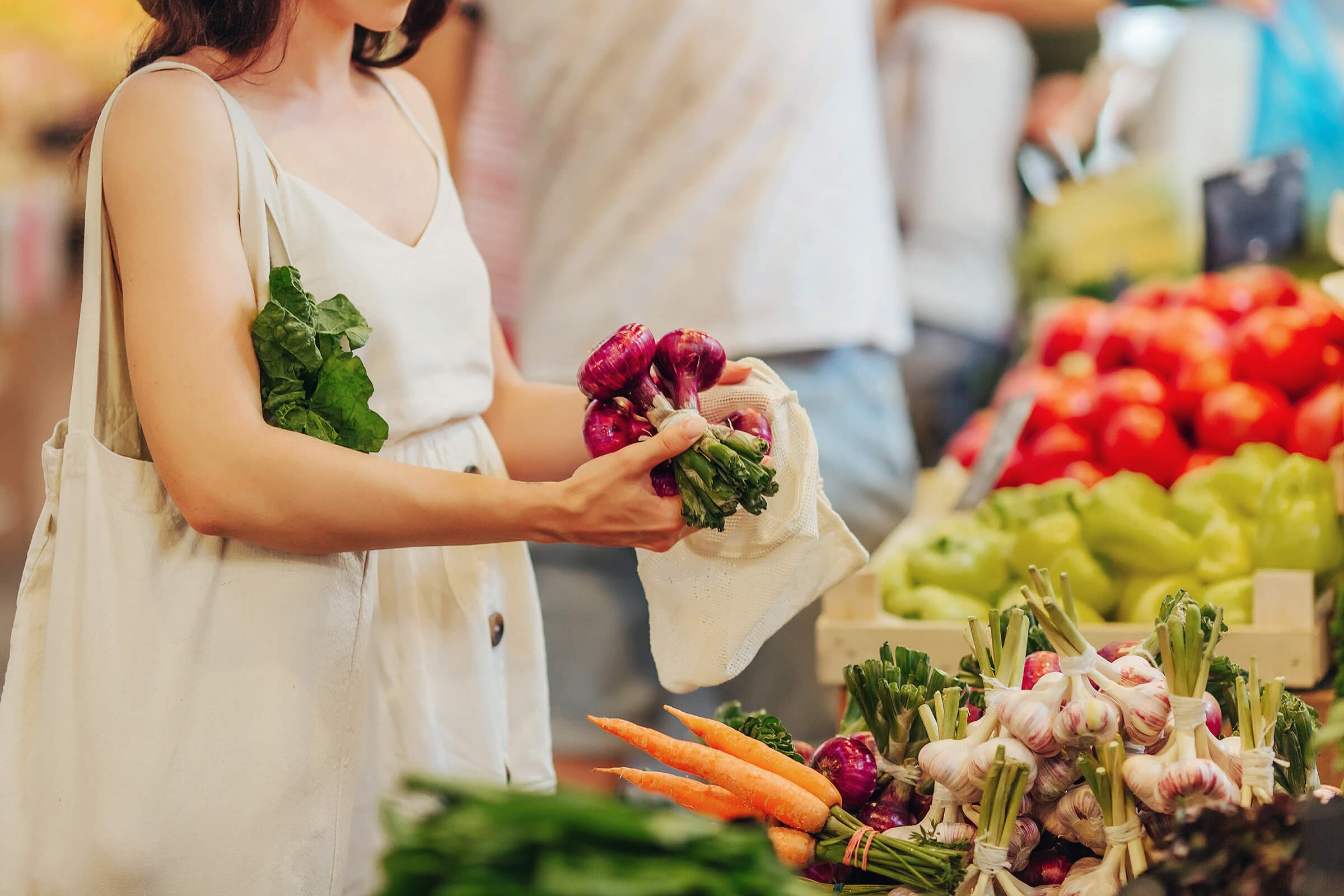 Lady picking red onions from market stall