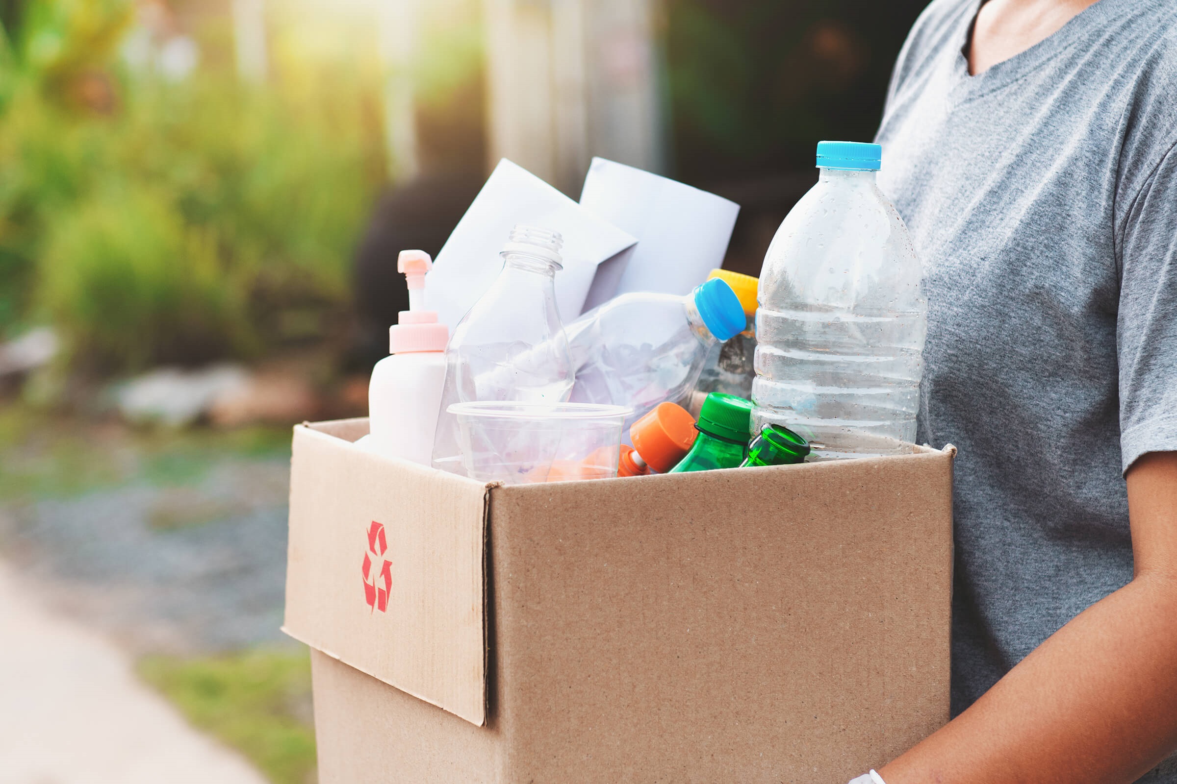 Person carrying box of empty plastic bottles